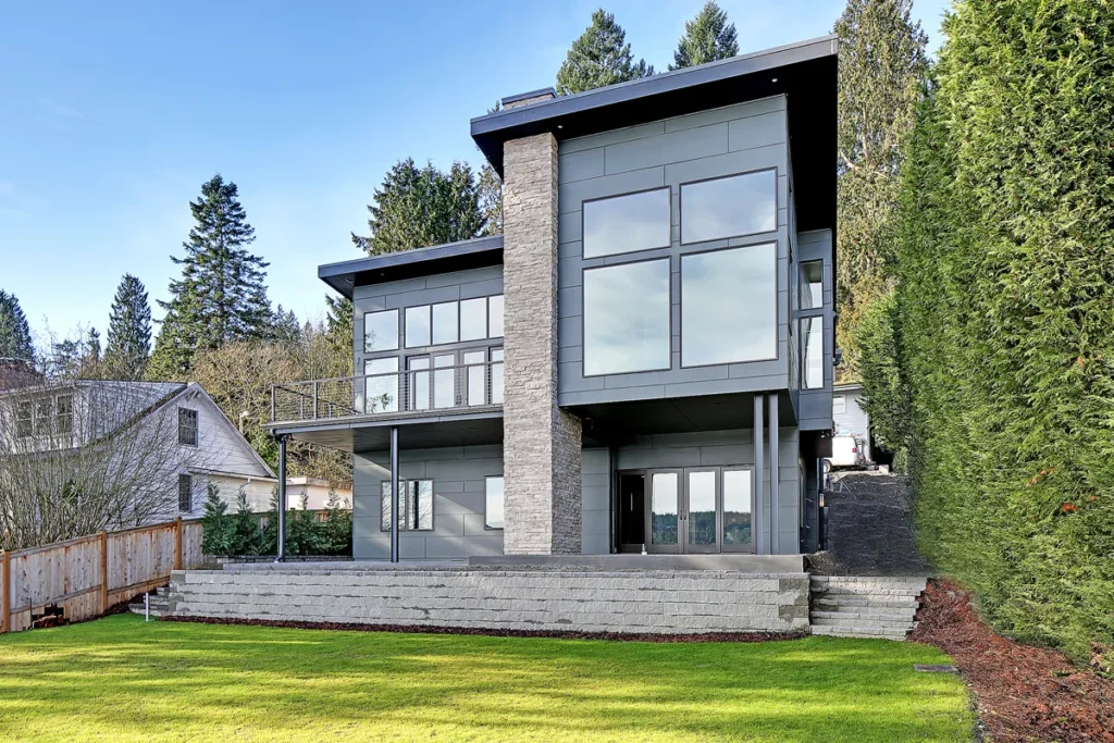 Rear exterior of a modern two-story home with large windows and mixed stone-and-siding cladding in the Seattle area, a second-story addition designed by Piper Cole Architects.