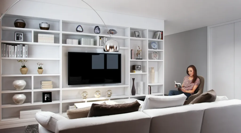 Finished basement living space with built-in white shelving, a media wall, and a sectional sofa, designed by Piper Cole Architects on the Seattle Eastside.