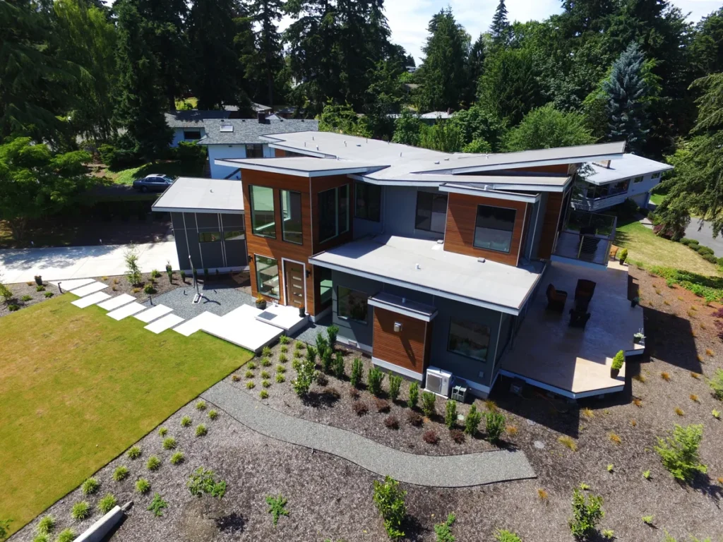 Aerial view of a contemporary custom home with mixed wood-and-metal cladding and landscaped grounds in the Seattle area, by Piper Cole Architects.