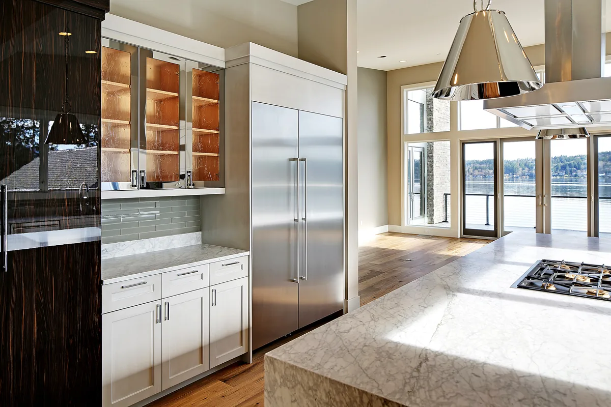 Renovated kitchen with white shaker and walnut cabinetry, stainless appliances, and a waterfront view near Seattle, by Piper Cole Architects.