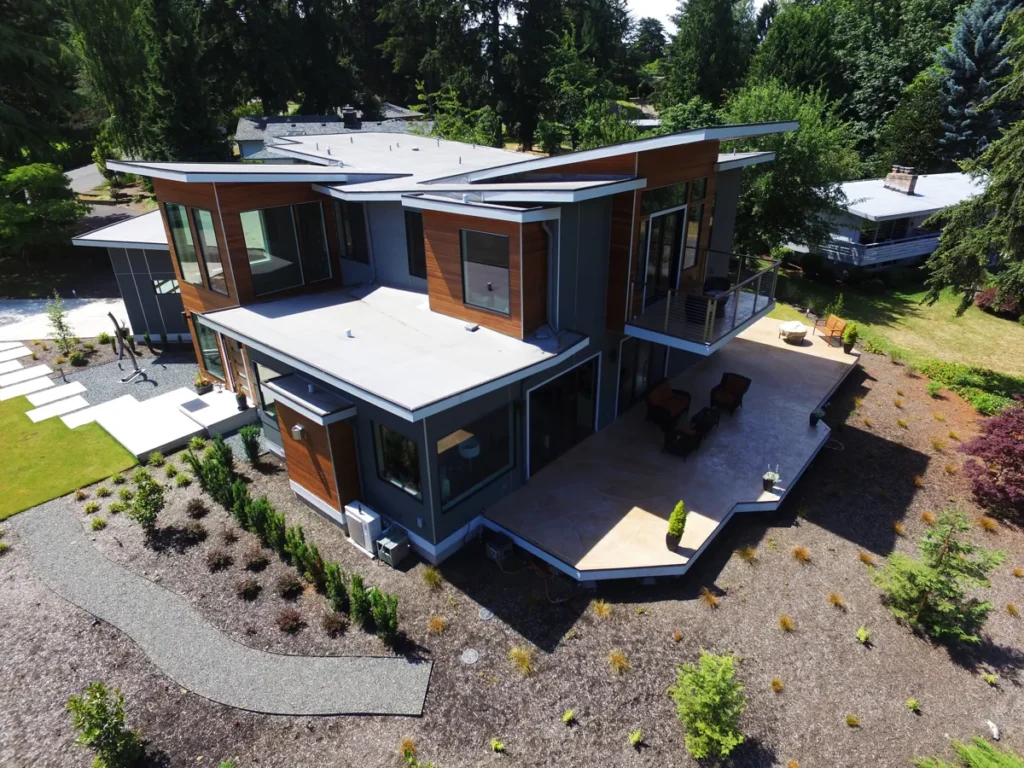 Aerial view of a modern Seattle-area home with flat rooflines, warm-wood accents, and landscaped grounds, designed by Piper Cole Architects.