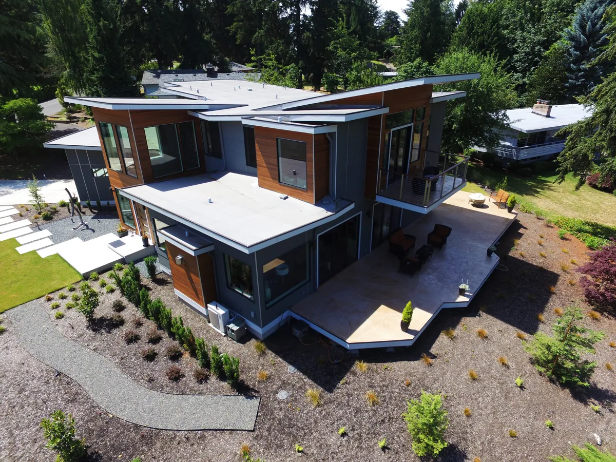 Aerial view of a modern Seattle-area home with flat rooflines, warm-wood accents, and landscaped grounds, designed by Piper Cole Architects.