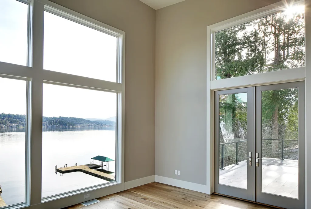Waterfront home interior with floor-to-ceiling windows and glass doors opening to a lake view and dock near Kirkland, designed by Piper Cole Architects.