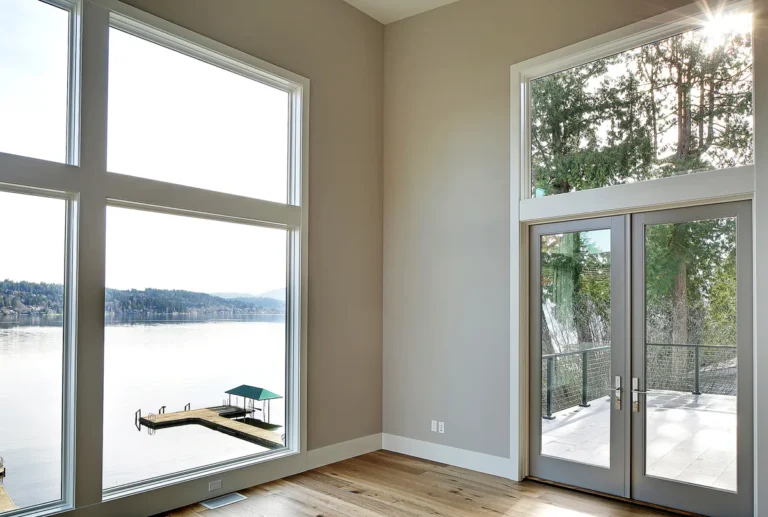 Waterfront home interior with floor-to-ceiling windows and glass doors opening to a lake view and dock near Kirkland, designed by Piper Cole Architects.