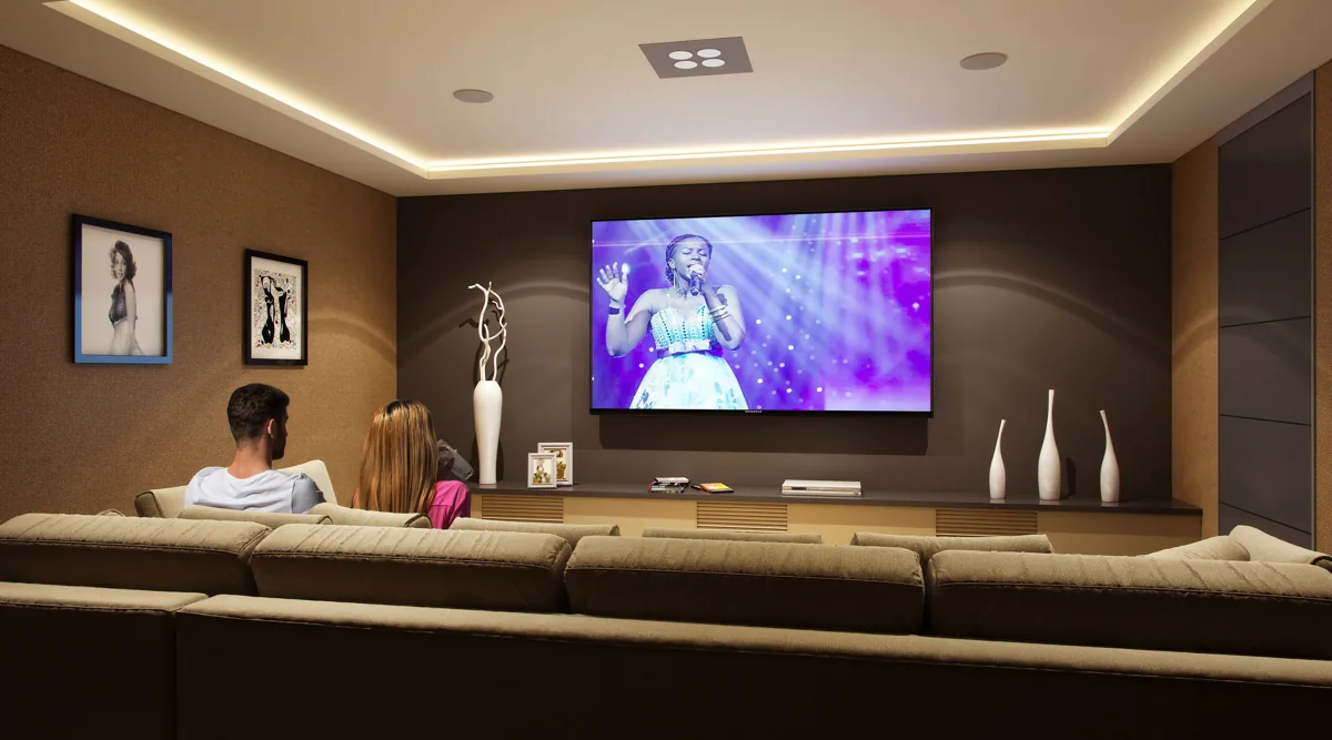 Finished media room with a large screen, layered lighting, and a sectional sofa in a remodeled Seattle-area home by Piper Cole Architects.