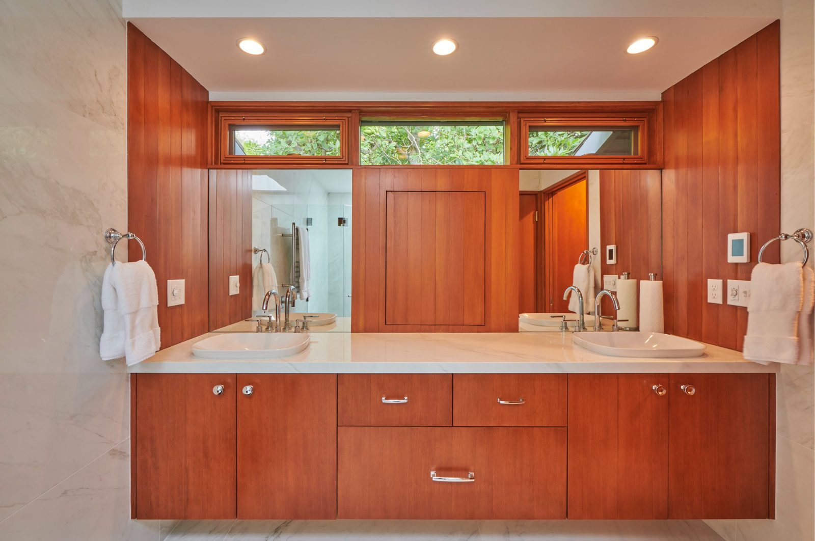 Primary bathroom with a long wood double vanity and clerestory windows