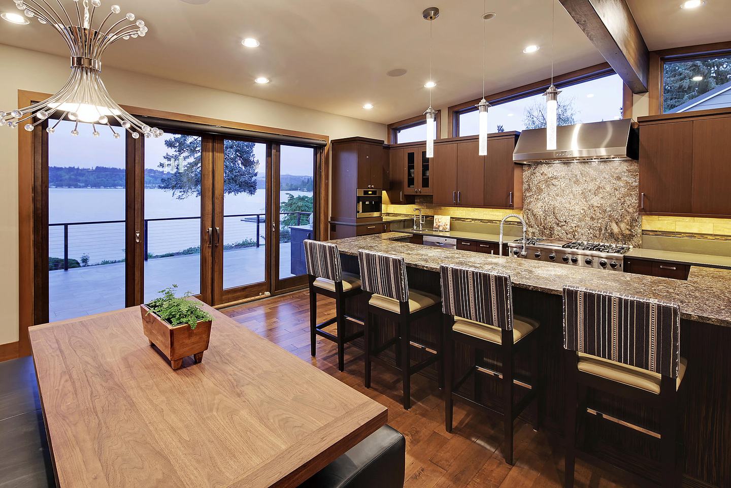 Kitchen with a long island, stone counters and a wall of windows facing the lake
