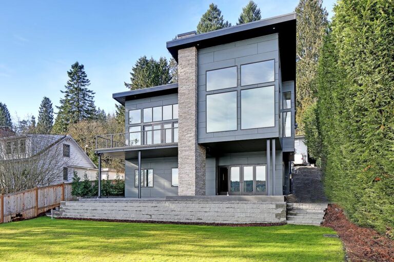 Contemporary two story house with stone column, metal panel siding, deck and lawn