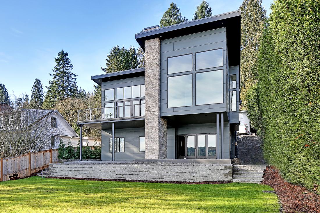 Contemporary two story house with stone column, metal panel siding, deck and lawn